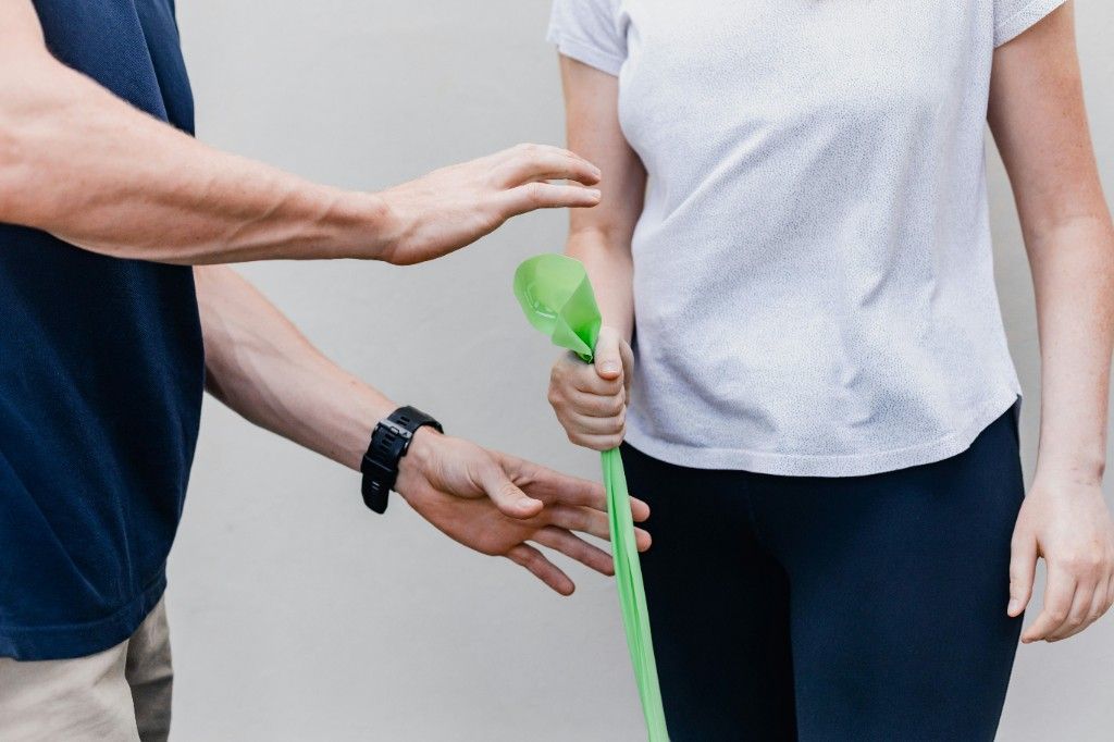 Une professionnelle accompagne une personne pendant un exercice avec une bande élastique.