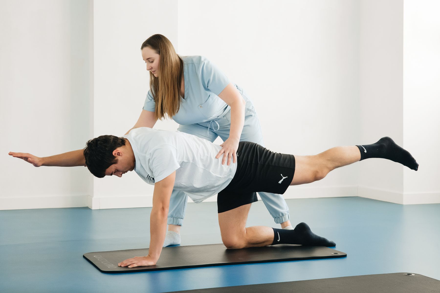 Une physiothérapeute accompagne une personne pendant un exercice de mouvement.